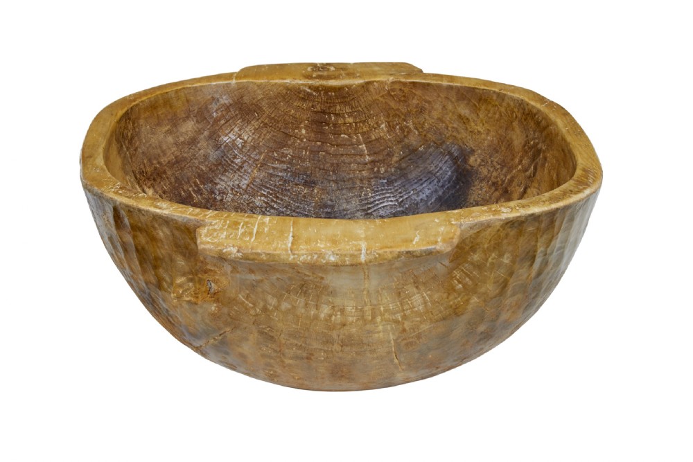A large hand-carved wooden bowl with integrated side handles and visible adze tool marks across the light brown timber surface. View VI