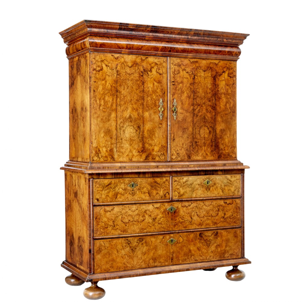 An 18th-century George I burr walnut cabinet on chest featuring double upper doors, brass keyhole escutcheons, and turned bun feet.