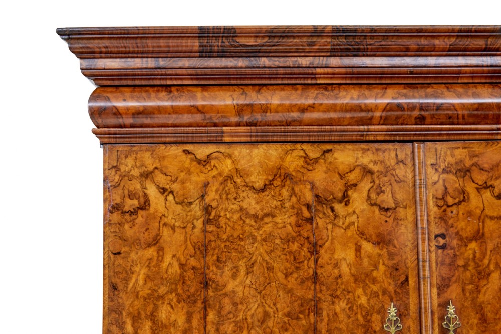 An 18th-century George I burr walnut cabinet on chest featuring double upper doors, brass keyhole escutcheons, and turned bun feet. View XVI