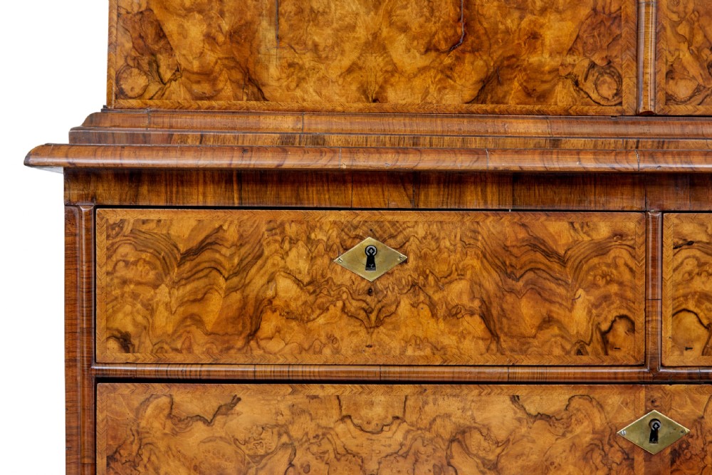 An 18th-century George I burr walnut cabinet on chest featuring double upper doors, brass keyhole escutcheons, and turned bun feet. View XVII