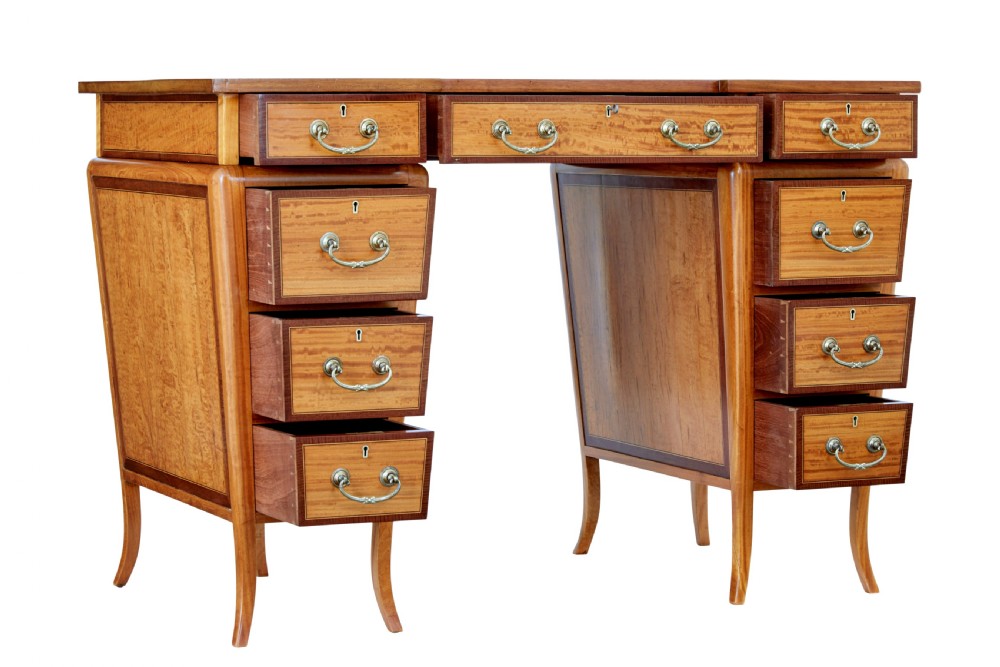 An early 20th-century Sheraton Revival satinwood pedestal desk featuring inlaid mahogany crossbanding, seven drawers with brass handles, and gently splayed legs. View II