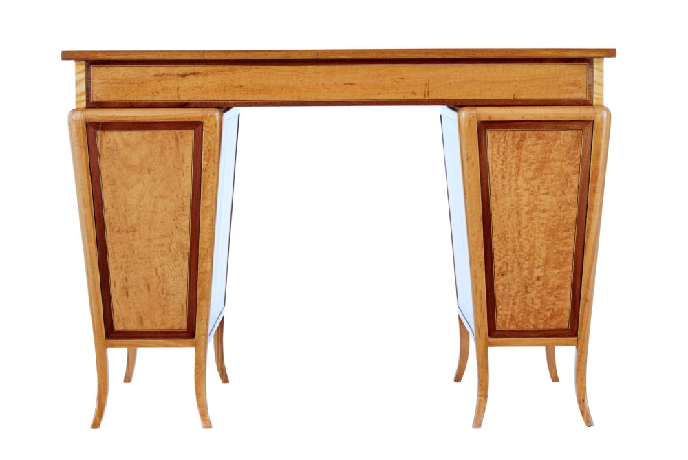 An early 20th-century Sheraton Revival satinwood pedestal desk featuring inlaid mahogany crossbanding, seven drawers with brass handles, and gently splayed legs. View VI