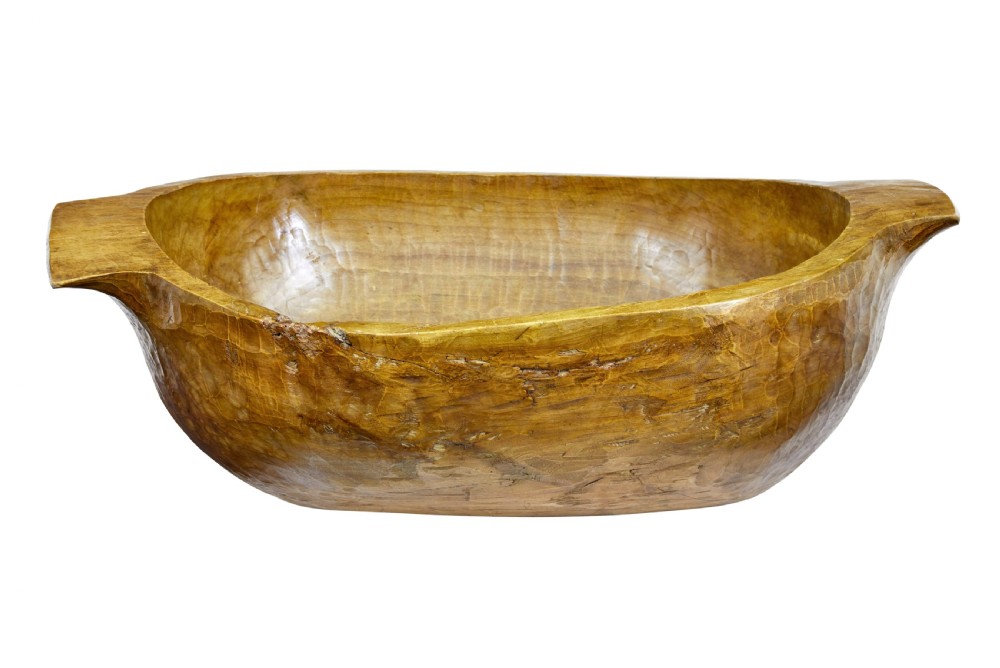 A large hand-carved wooden dough bowl with integrated end handles and a polished warm brown finish displaying visible adze marks. View III
