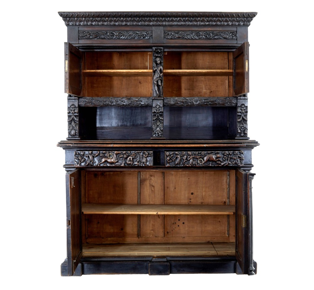 A large 19th-century Flemish dark carved oak cabinet featuring intricate relief panels depicting human figures and architectural details. View II