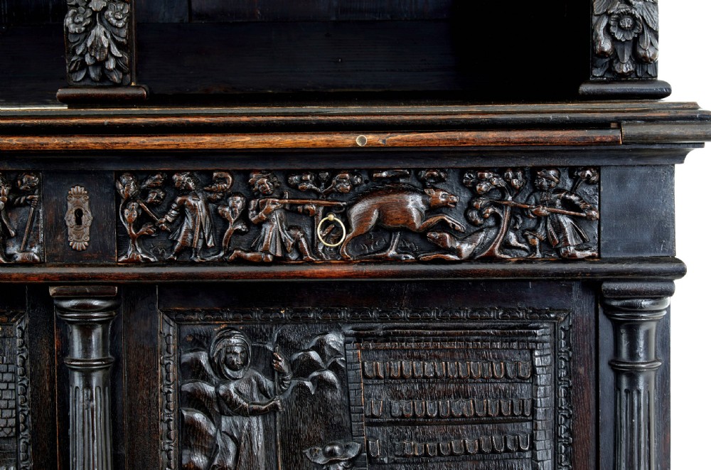 A large 19th-century Flemish dark carved oak cabinet featuring intricate relief panels depicting human figures and architectural details. View VII