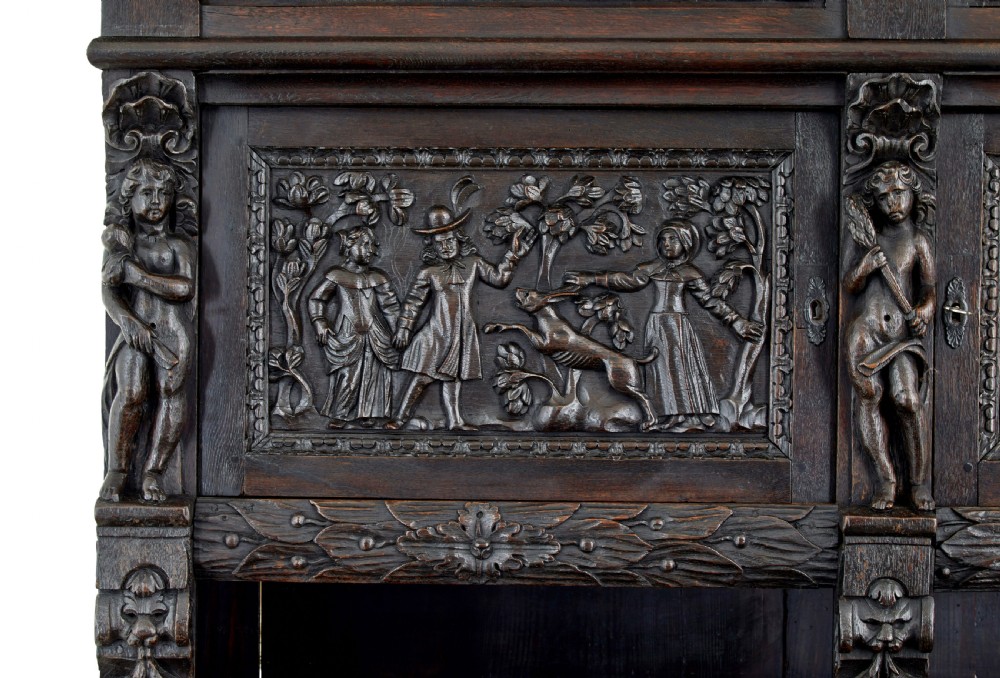 A large 19th-century Flemish dark carved oak cabinet featuring intricate relief panels depicting human figures and architectural details. View XI