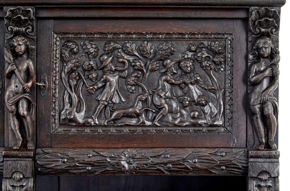 A large 19th-century Flemish dark carved oak cabinet featuring intricate relief panels depicting human figures and architectural details. View XII