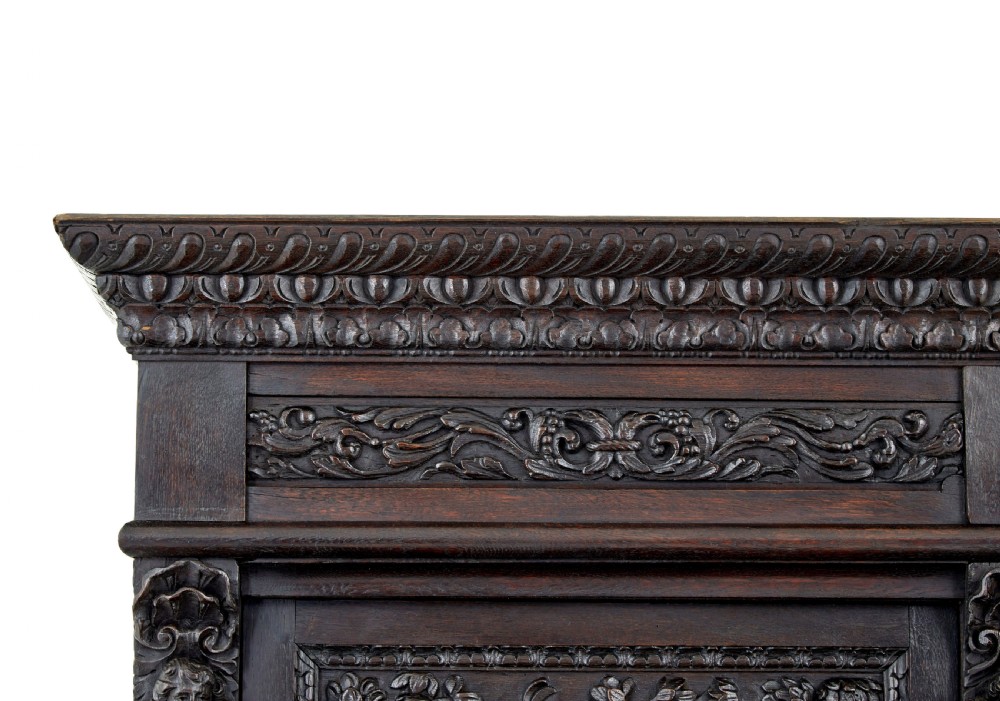 A large 19th-century Flemish dark carved oak cabinet featuring intricate relief panels depicting human figures and architectural details. View XIII