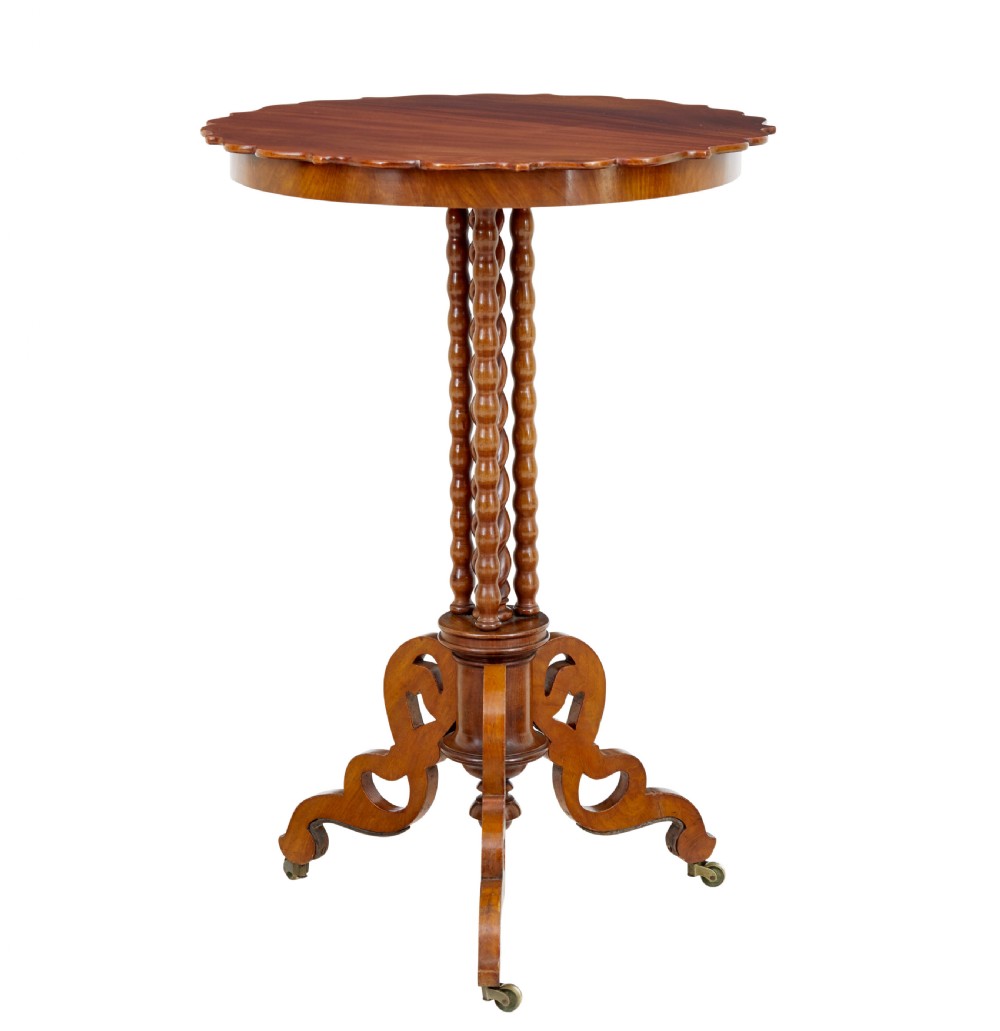 A late 19th-century mahogany occasional table featuring a scalloped piecrust top, central bobbin-turned supports, and a tripod scroll base with brass castors. View II