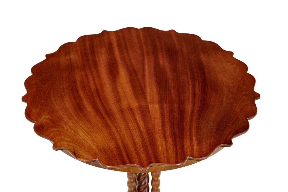 A late 19th-century mahogany occasional table featuring a scalloped piecrust top, central bobbin-turned supports, and a tripod scroll base with brass castors. View V