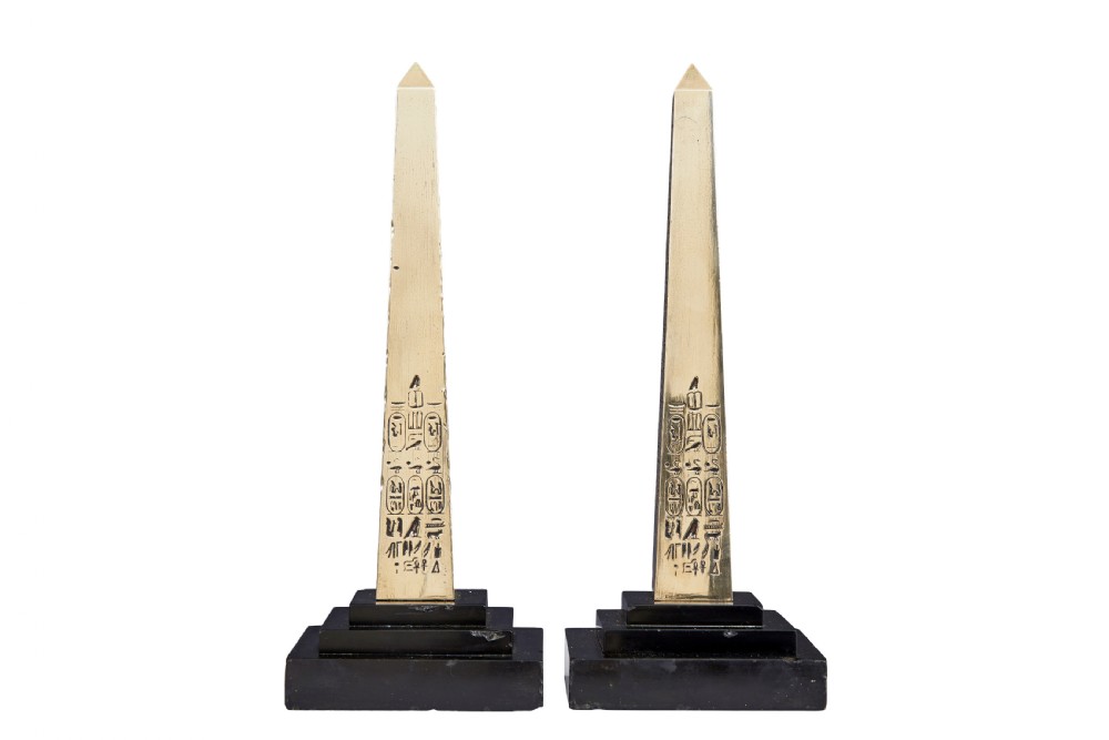 A pair of brass obelisks with incised hieroglyphic carvings mounted on stepped black marble bases. View IV