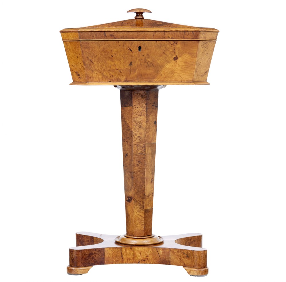 A nineteenth-century Swedish burr elm teapoy featuring an octagonal casket lid, a faceted pedestal column, and a shaped plinth base.
