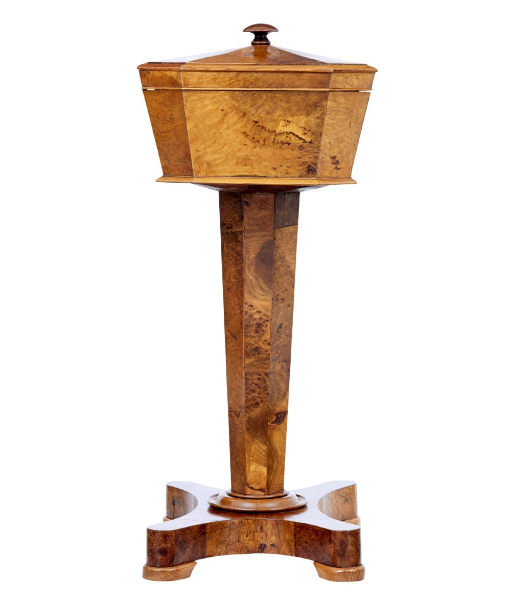 A nineteenth-century Swedish burr elm teapoy featuring an octagonal casket lid, a faceted pedestal column, and a shaped plinth base. View VI