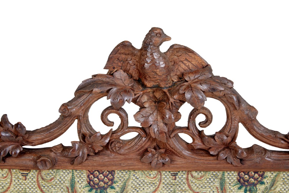 A carved oak tripod fire screen with a crest carved as a bird surrounding a woven tapestry panel featuring pineapple motifs. View II