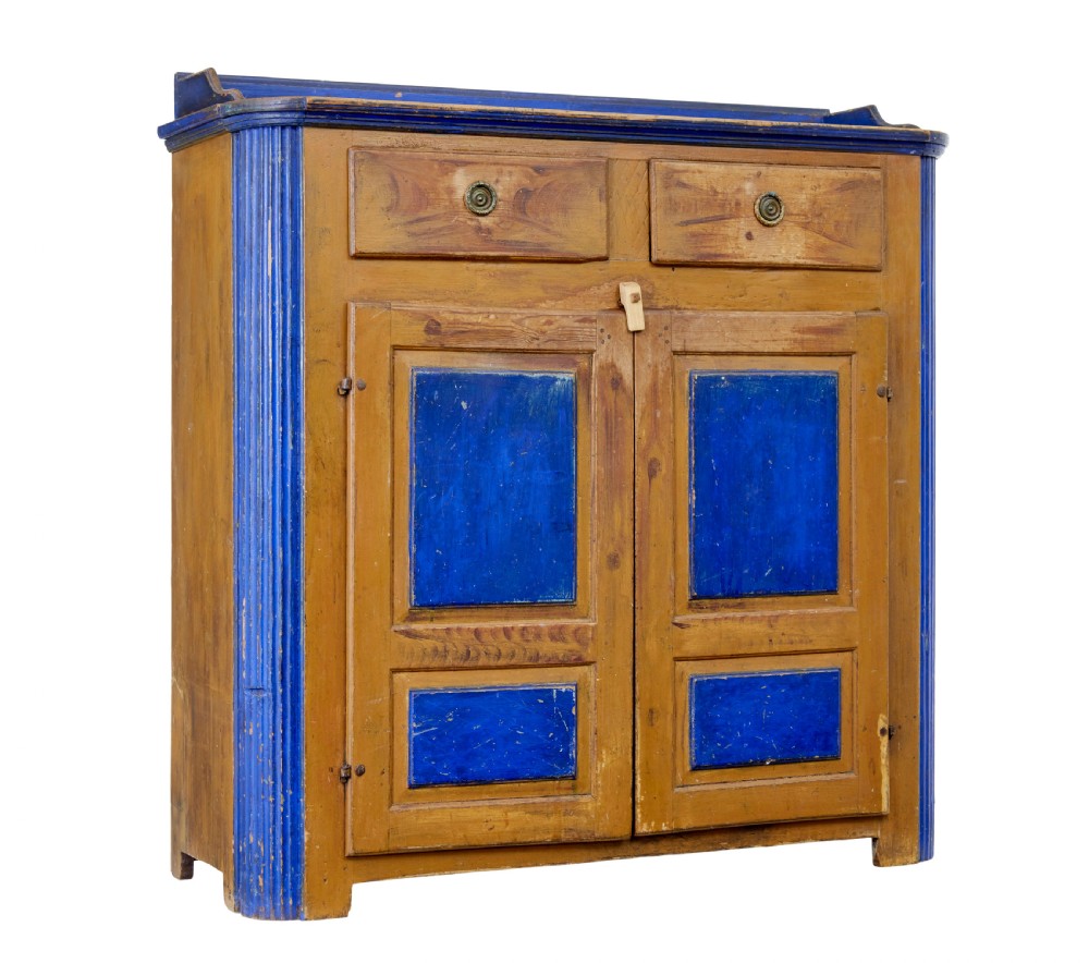 A 19th-century Swedish pine kitchen cupboard with ochre faux-grained body, vibrant blue fluted columns, two top drawers, and blue panelled double doors.