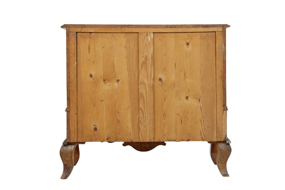 An early nineteenth-century Swedish oak chest of drawers featuring detailed botanical wood inlay, a carved apron, and decorative brass hardware. View VI