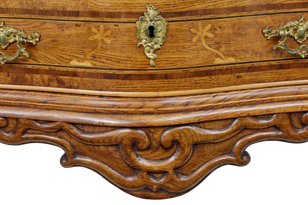 An early nineteenth-century Swedish oak chest of drawers featuring detailed botanical wood inlay, a carved apron, and decorative brass hardware. View VIII