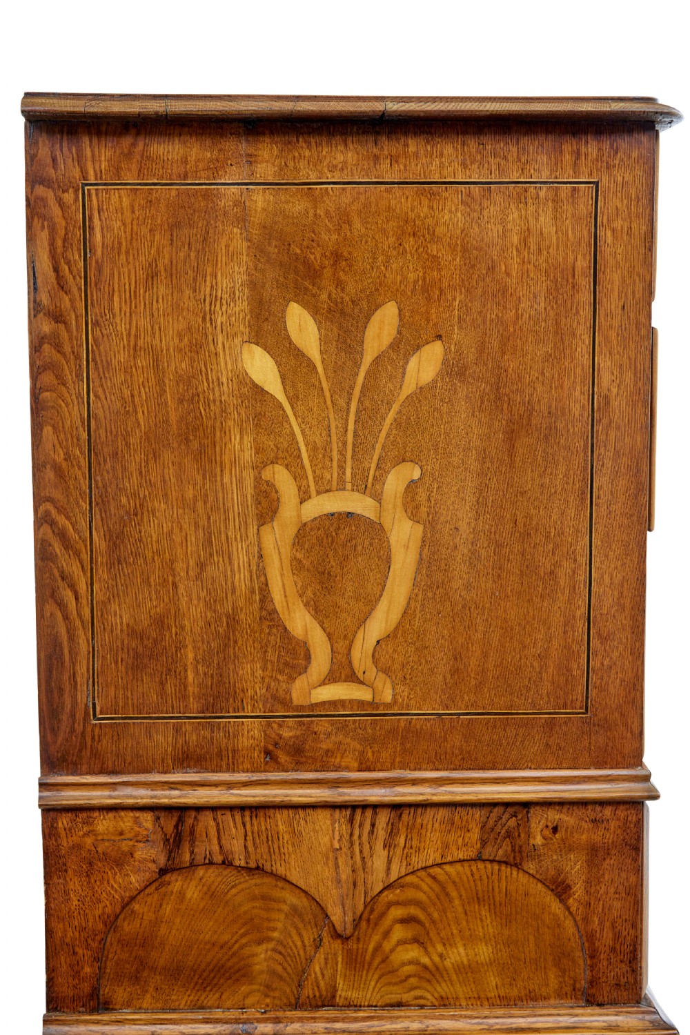 An early nineteenth-century Swedish oak chest of drawers featuring detailed botanical wood inlay, a carved apron, and decorative brass hardware. View X