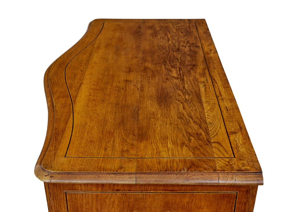 An early nineteenth-century Swedish oak chest of drawers featuring detailed botanical wood inlay, a carved apron, and decorative brass hardware. View XII