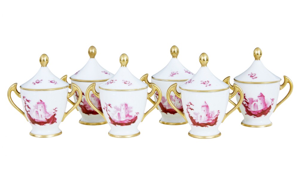 A seven-piece French porcelain dessert set featuring six twin-handled covered cream pots and a matching shaped tray, decorated with pink landscape scenes and gilded handles. View V