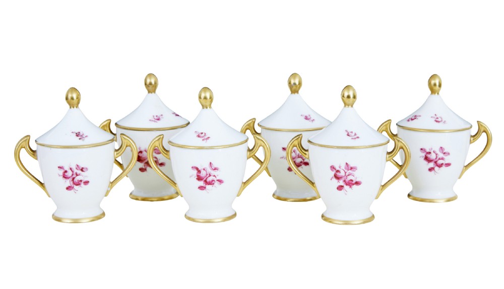 A seven-piece French porcelain dessert set featuring six twin-handled covered cream pots and a matching shaped tray, decorated with pink landscape scenes and gilded handles. View VI
