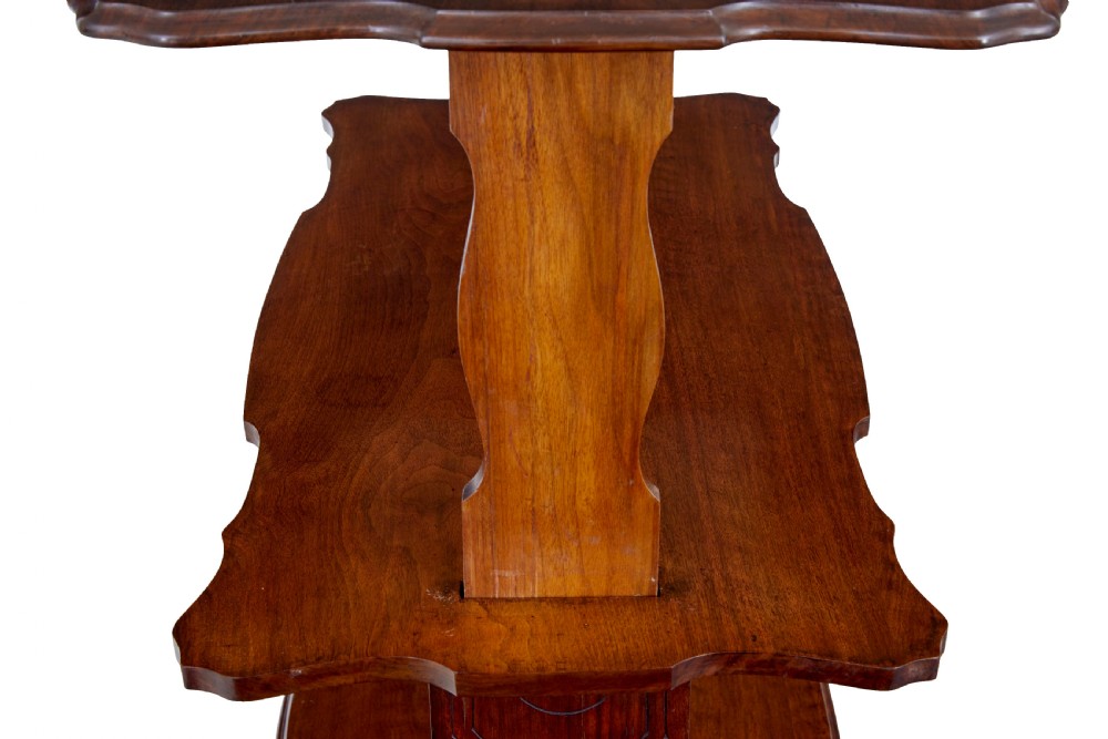 A 19th-century Victorian walnut metamorphic dumb waiter featuring a serpentine moulded top, carved C-scroll side supports, a turned stretcher, and brass castors. View VIII