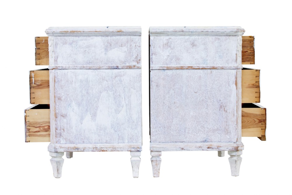 A pair of 19th-century Swedish chests of drawers featuring three drawers each, diamond lattice carvings on the top drawer front, brass handles, and a distressed white paint finish. View III