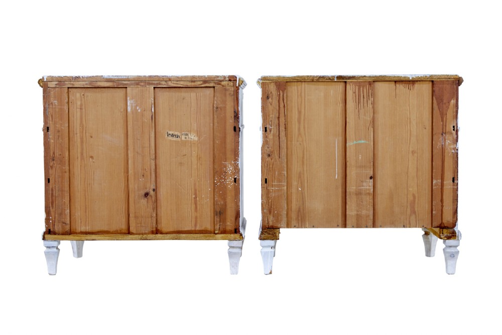 A pair of 19th-century Swedish chests of drawers featuring three drawers each, diamond lattice carvings on the top drawer front, brass handles, and a distressed white paint finish. View VI