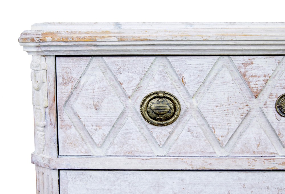 A pair of 19th-century Swedish chests of drawers featuring three drawers each, diamond lattice carvings on the top drawer front, brass handles, and a distressed white paint finish. View VII