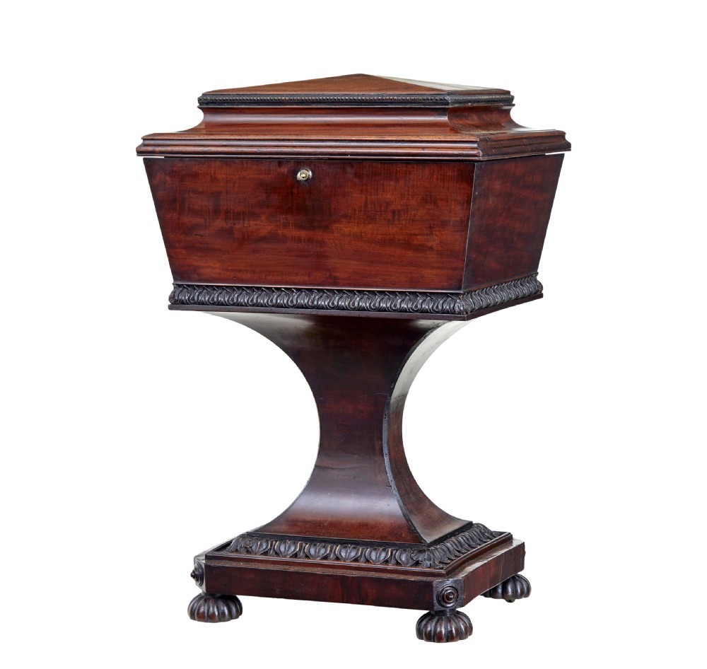 A 19th-century carved mahogany teapoy featuring a stepped hinged lid, flared central pedestal base, and carved feet.