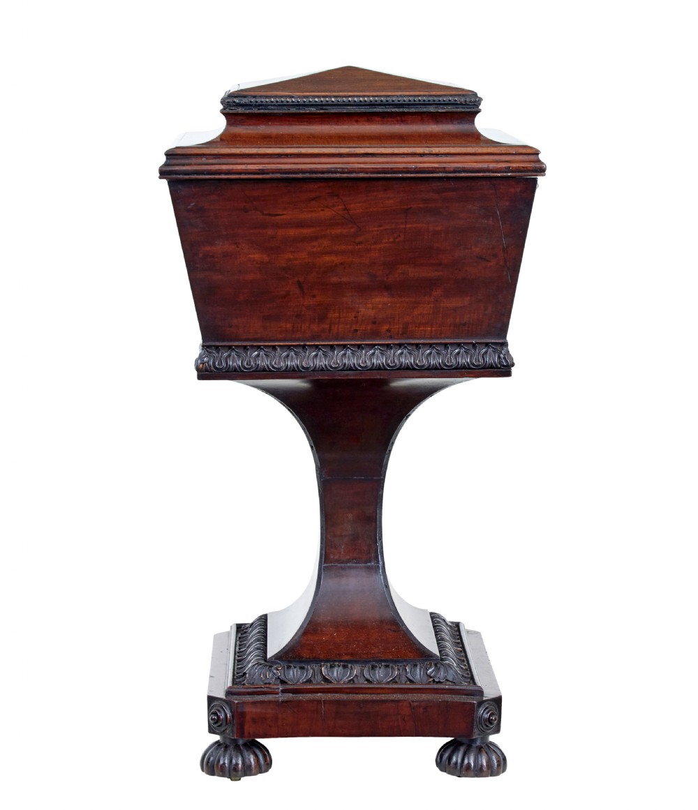 A 19th-century carved mahogany teapoy featuring a stepped hinged lid, flared central pedestal base, and carved feet. View V