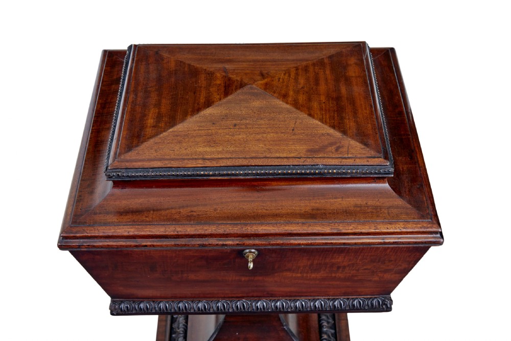 A 19th-century carved mahogany teapoy featuring a stepped hinged lid, flared central pedestal base, and carved feet. View VI
