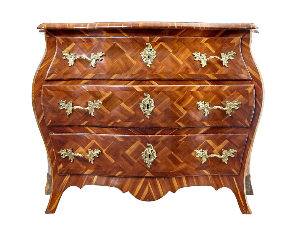An early 18th-century Rococo bombe chest of drawers featuring geometric parquetry inlay in plumwood and three drawers with ornate brass handles. View III