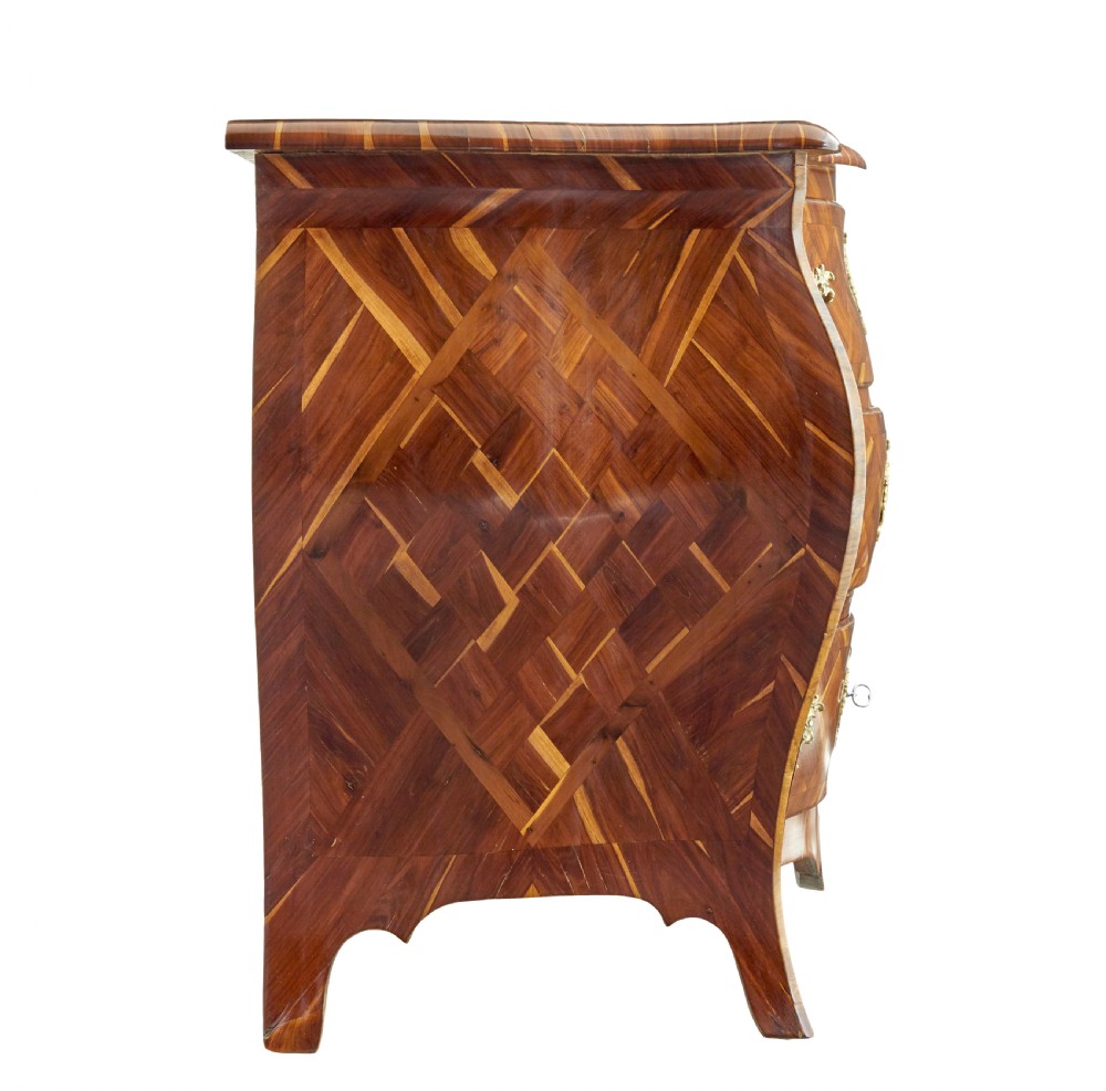 An early 18th-century Rococo bombe chest of drawers featuring geometric parquetry inlay in plumwood and three drawers with ornate brass handles. View VII