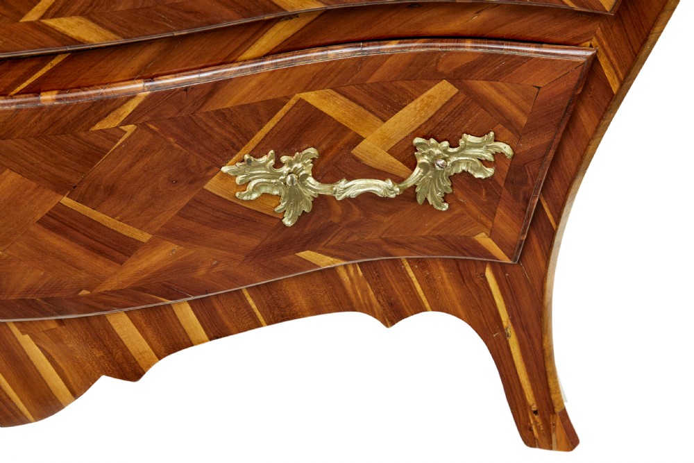 An early 18th-century Rococo bombe chest of drawers featuring geometric parquetry inlay in plumwood and three drawers with ornate brass handles. View VIII