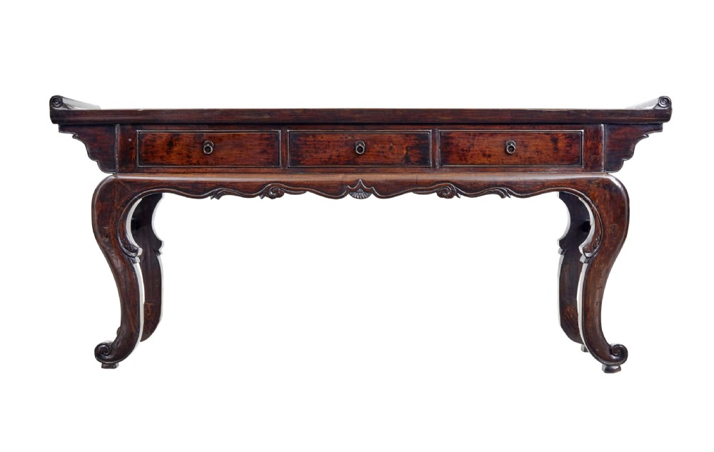 A nineteenth-century dark lacquered Chinese hardwood altar table with three drawers, everted end flanges, carved aprons, and curved legs. View II