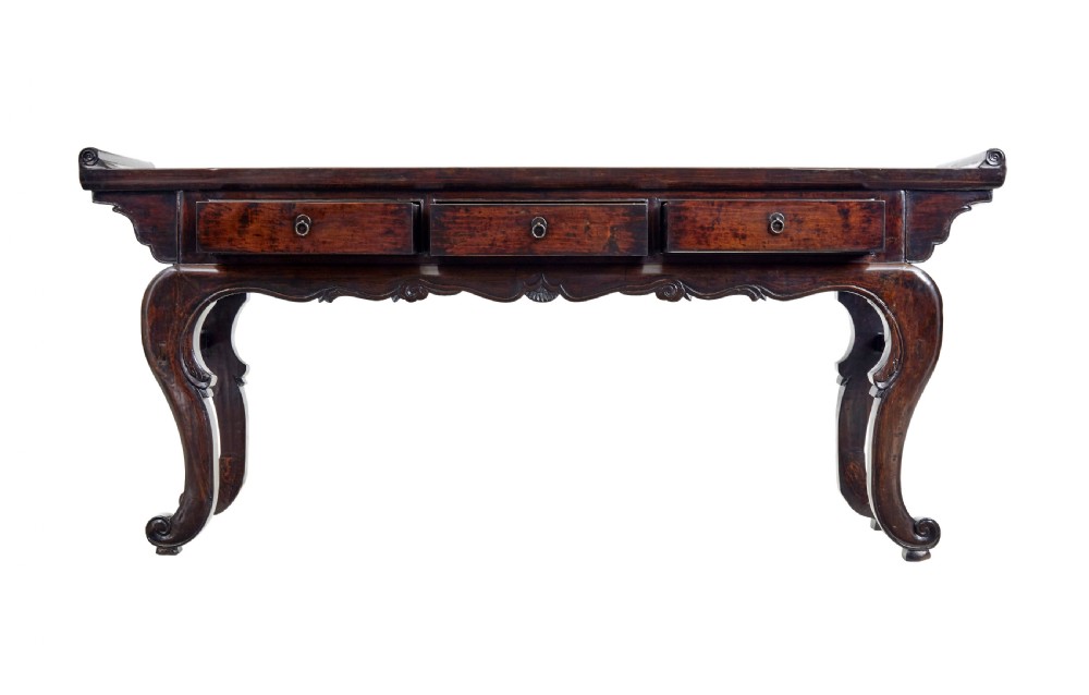 A nineteenth-century dark lacquered Chinese hardwood altar table with three drawers, everted end flanges, carved aprons, and curved legs. View III