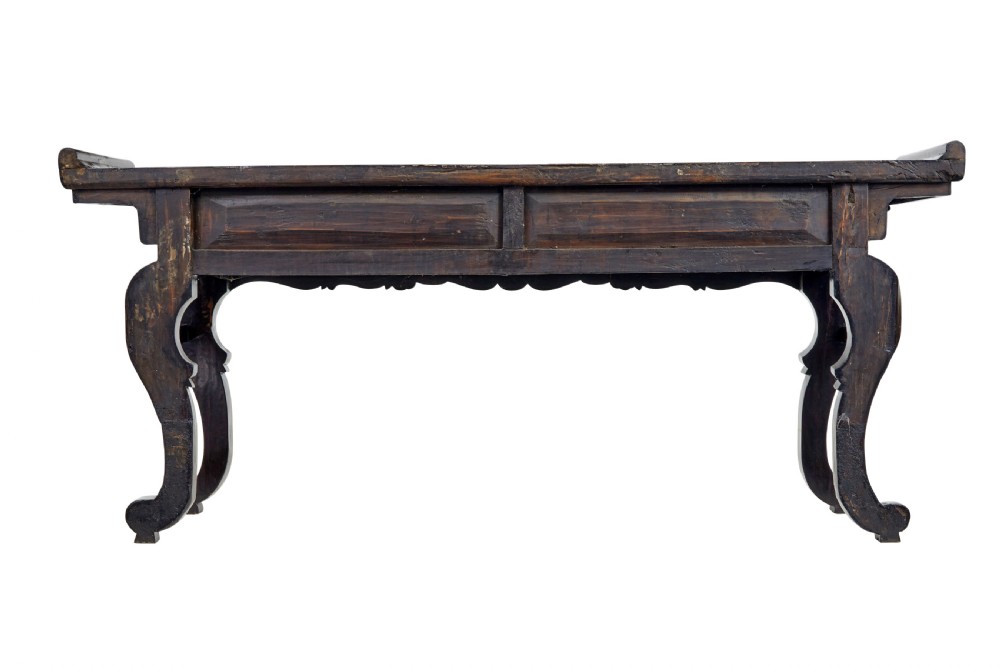 A nineteenth-century dark lacquered Chinese hardwood altar table with three drawers, everted end flanges, carved aprons, and curved legs. View V