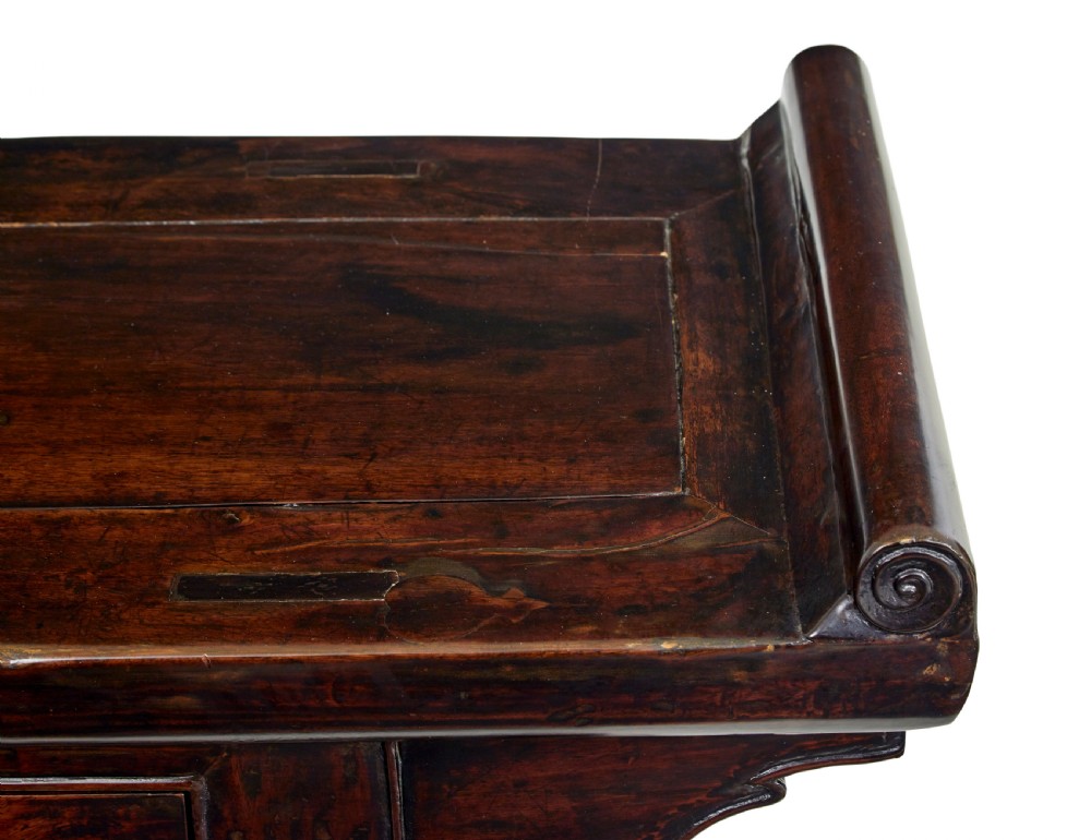 A nineteenth-century dark lacquered Chinese hardwood altar table with three drawers, everted end flanges, carved aprons, and curved legs. View IX