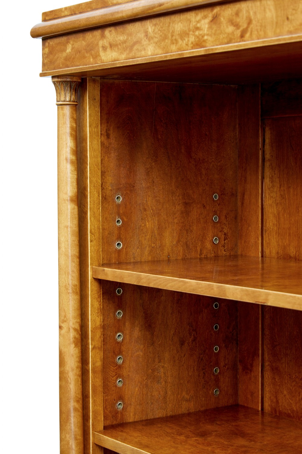 An early twentieth-century Empire Revival satin birch bookcase cabinet featuring open adjustable upper shelving and three lower panelled cupboard doors with a central carved drape motif. View X