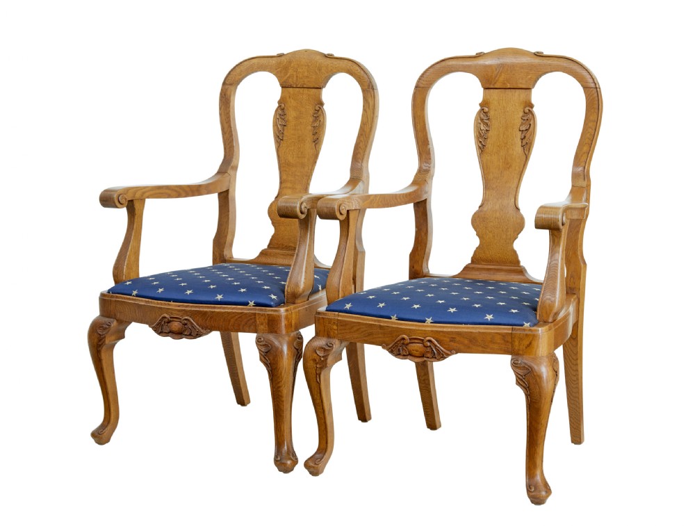 A pair of 19th-century carved oak open armchairs featuring vasiform splats, cabriole legs, carved seat aprons, and blue star-patterned upholstery.