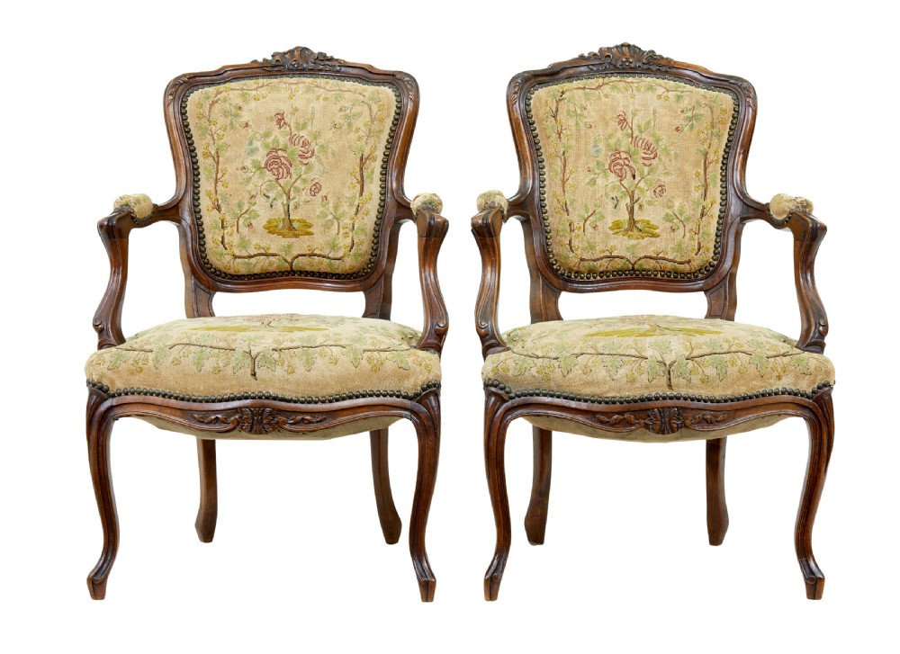 A pair of 19th-century French fauteuil armchairs with carved walnut frames and floral needlepoint upholstered seats and backs.