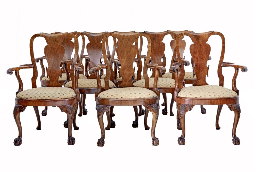 A set of carved walnut dining chairs featuring vasiform splat backs, upholstered drop-in seats, and cabriole legs ending in claw and ball feet.