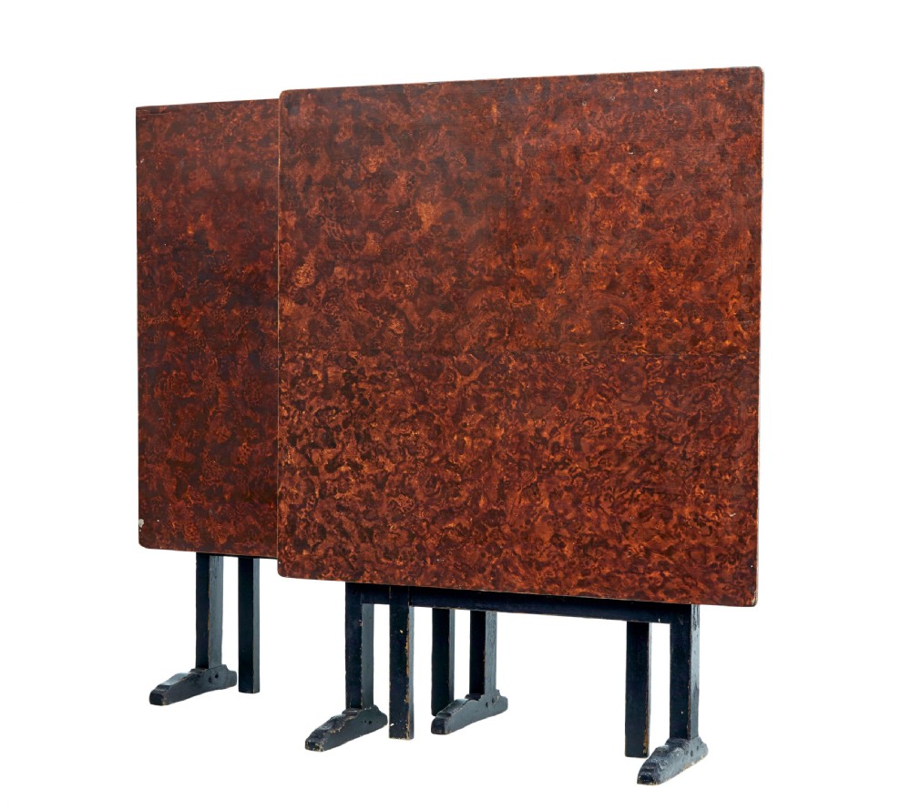 A pair of 19th-century Swedish folding tables featuring square tops with mottled brown ragwork painted surfaces supported on dark painted trestle bases.