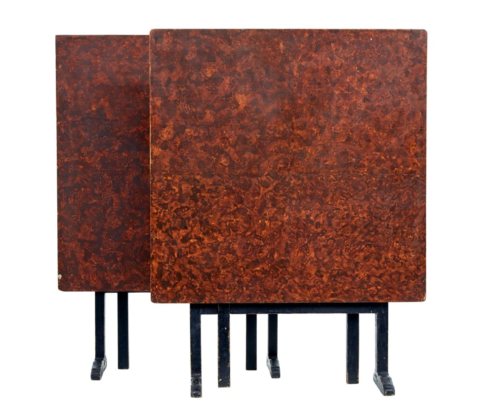 A pair of 19th-century Swedish folding tables featuring square tops with mottled brown ragwork painted surfaces supported on dark painted trestle bases. View II