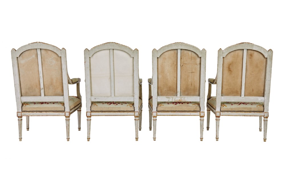 A five-piece French giltwood salon suite comprising four carved armchairs and a matching sofa, all upholstered in cream woven tapestry with floral and figurative medallions. View V