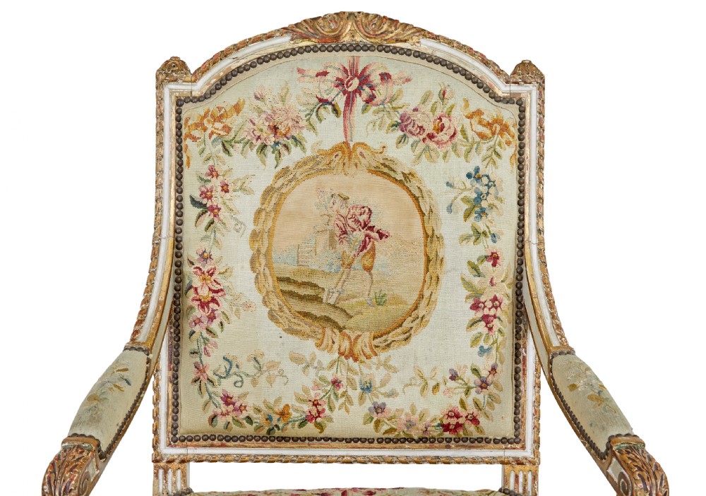 A five-piece French giltwood salon suite comprising four carved armchairs and a matching sofa, all upholstered in cream woven tapestry with floral and figurative medallions. View VI