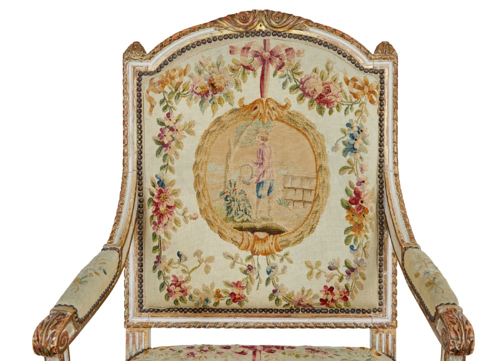 A five-piece French giltwood salon suite comprising four carved armchairs and a matching sofa, all upholstered in cream woven tapestry with floral and figurative medallions. View VII