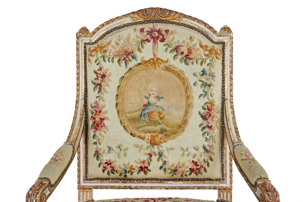 A five-piece French giltwood salon suite comprising four carved armchairs and a matching sofa, all upholstered in cream woven tapestry with floral and figurative medallions. View VIII