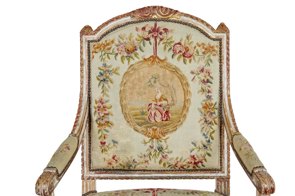 A five-piece French giltwood salon suite comprising four carved armchairs and a matching sofa, all upholstered in cream woven tapestry with floral and figurative medallions. View IX